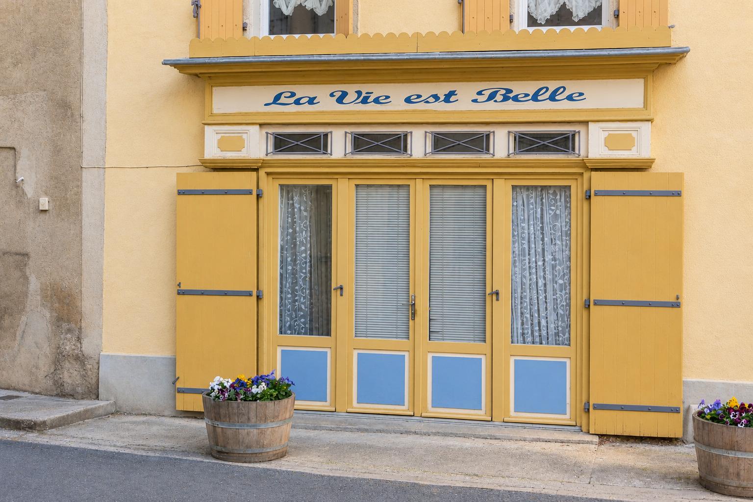 Yellow shopfront of a traditional village shop in the Aude: “La Vie est Belle”
