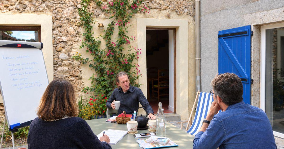 Mini-group French lesson in the school courtyard: the teacher and two learners around a table, with a flipchart
