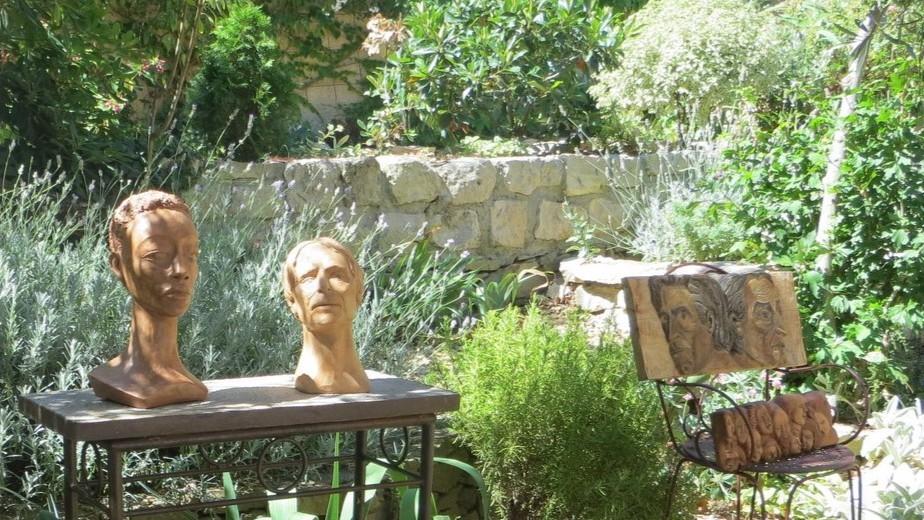 Terracotta busts and a carved wooden relief displayed in a Mediterranean garden